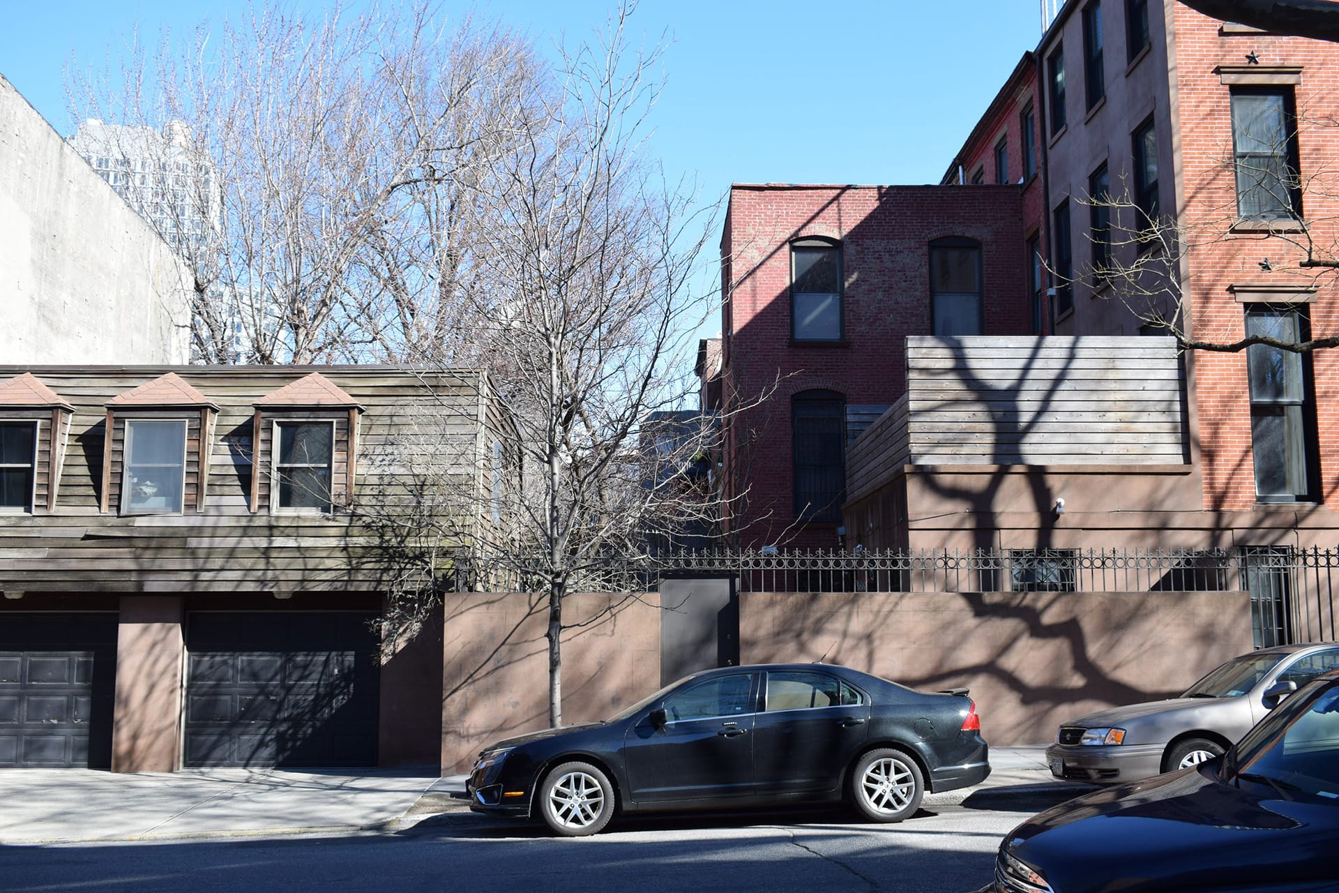 Side view of a Park Slope corner home with a four-story townhouse, two-story detached rear garage, and courtyard in between