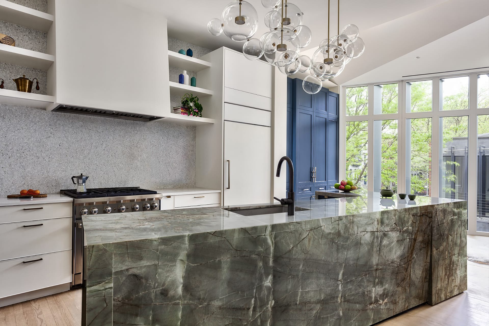 Kitchen in a Park Slope townhome with a large marble island, blue cabinetry, and bubble light fixture