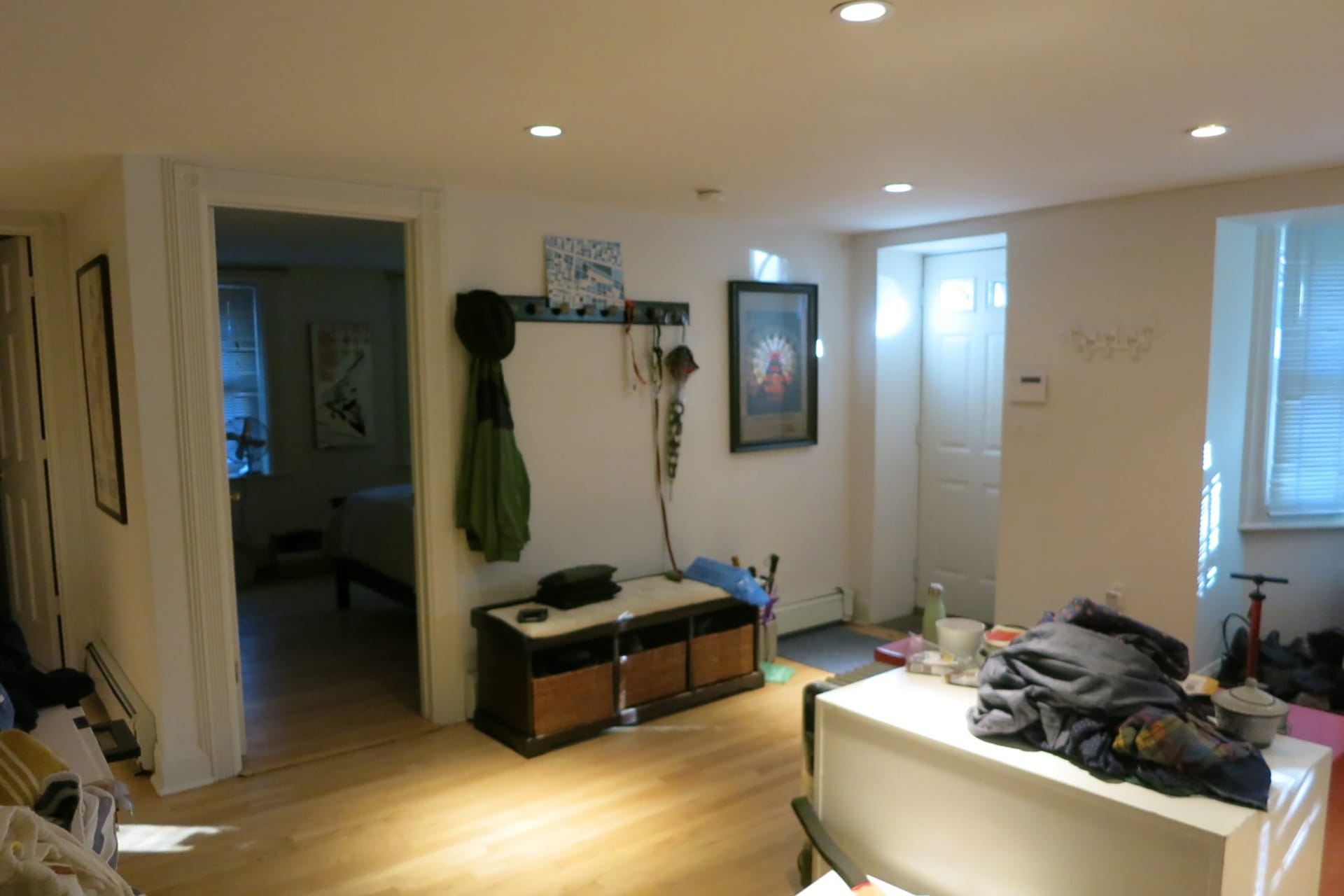 Garden level entryway and guest bedroom with light wood floors and recessed lighting