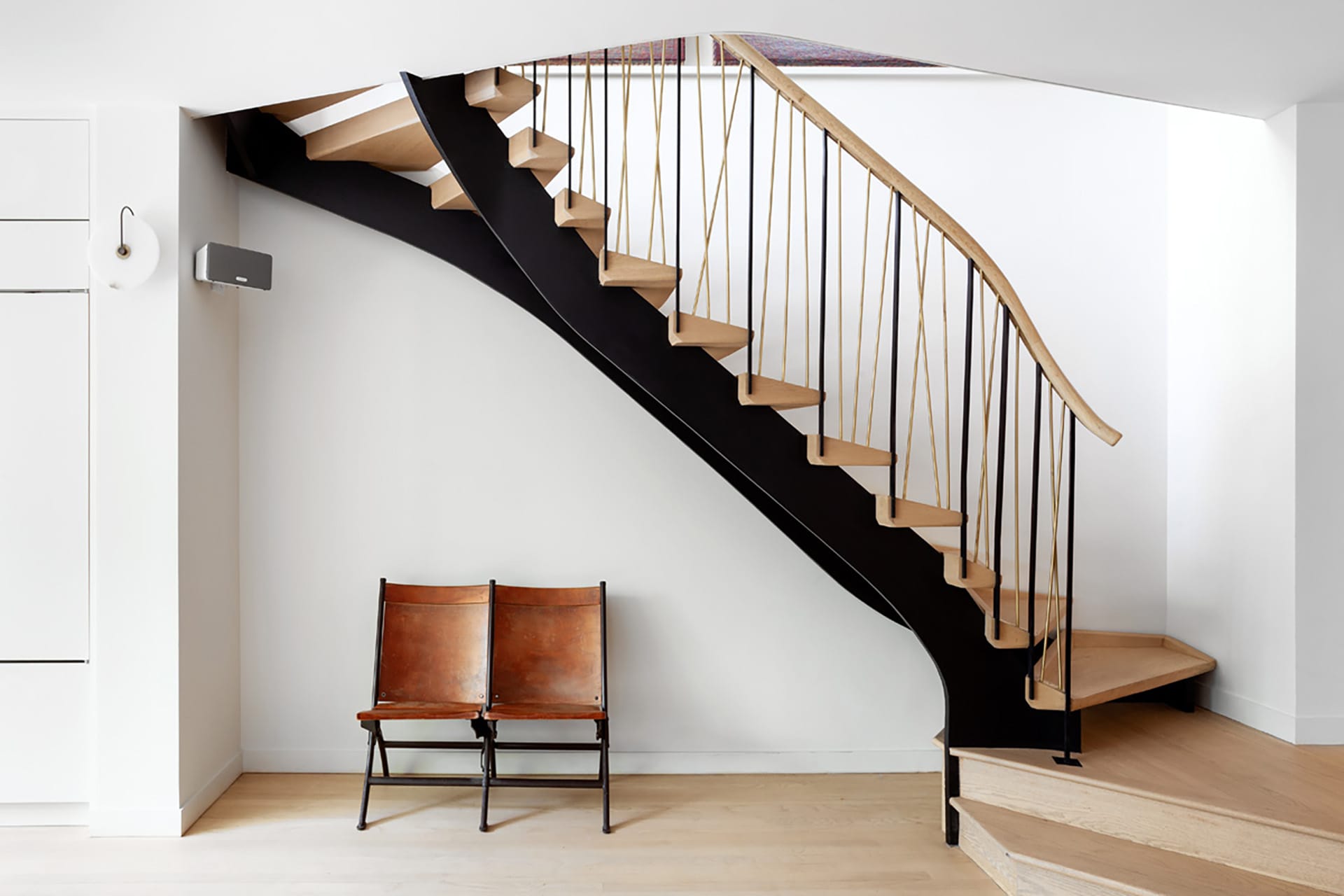 Staircase in a Park Slope home with custom railings and risers, and a double chair underneath