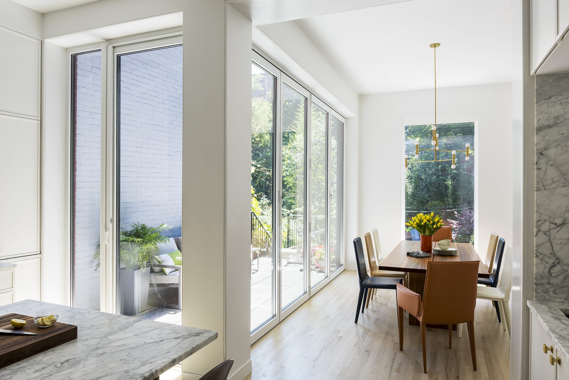 Narrow extension in a Park Slope home converted into a dining area with large sliding glass NanaWalls leading out to the rear yard