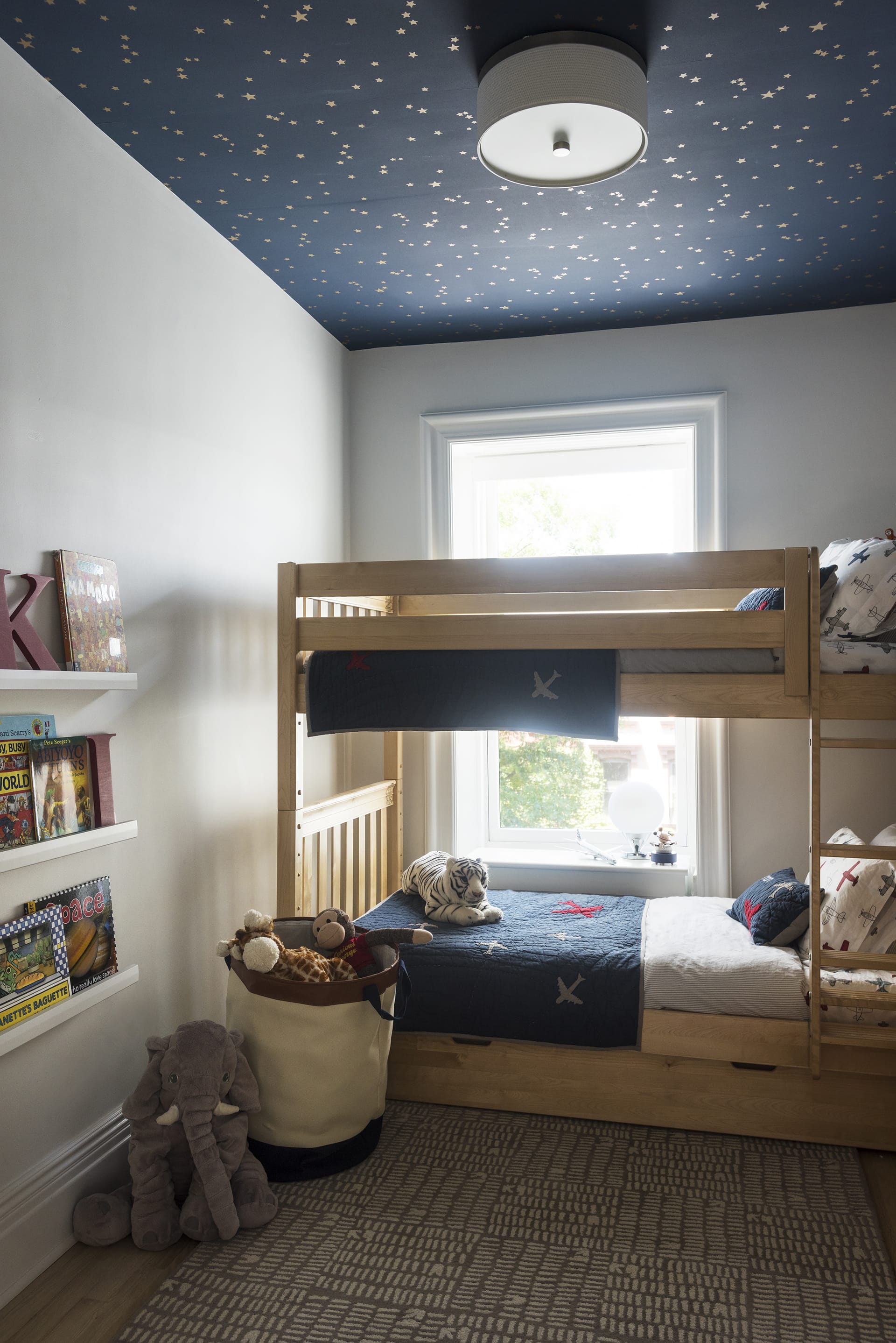 Children's room with bunk beds and a night sky mural on the ceiling