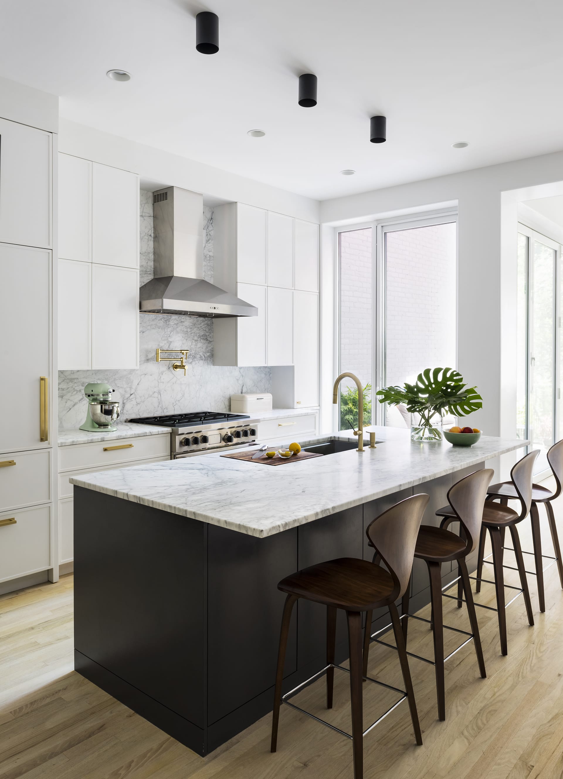 Kitchen in a Prospect Heights home with white millwork, a black island, and white marble countertops.