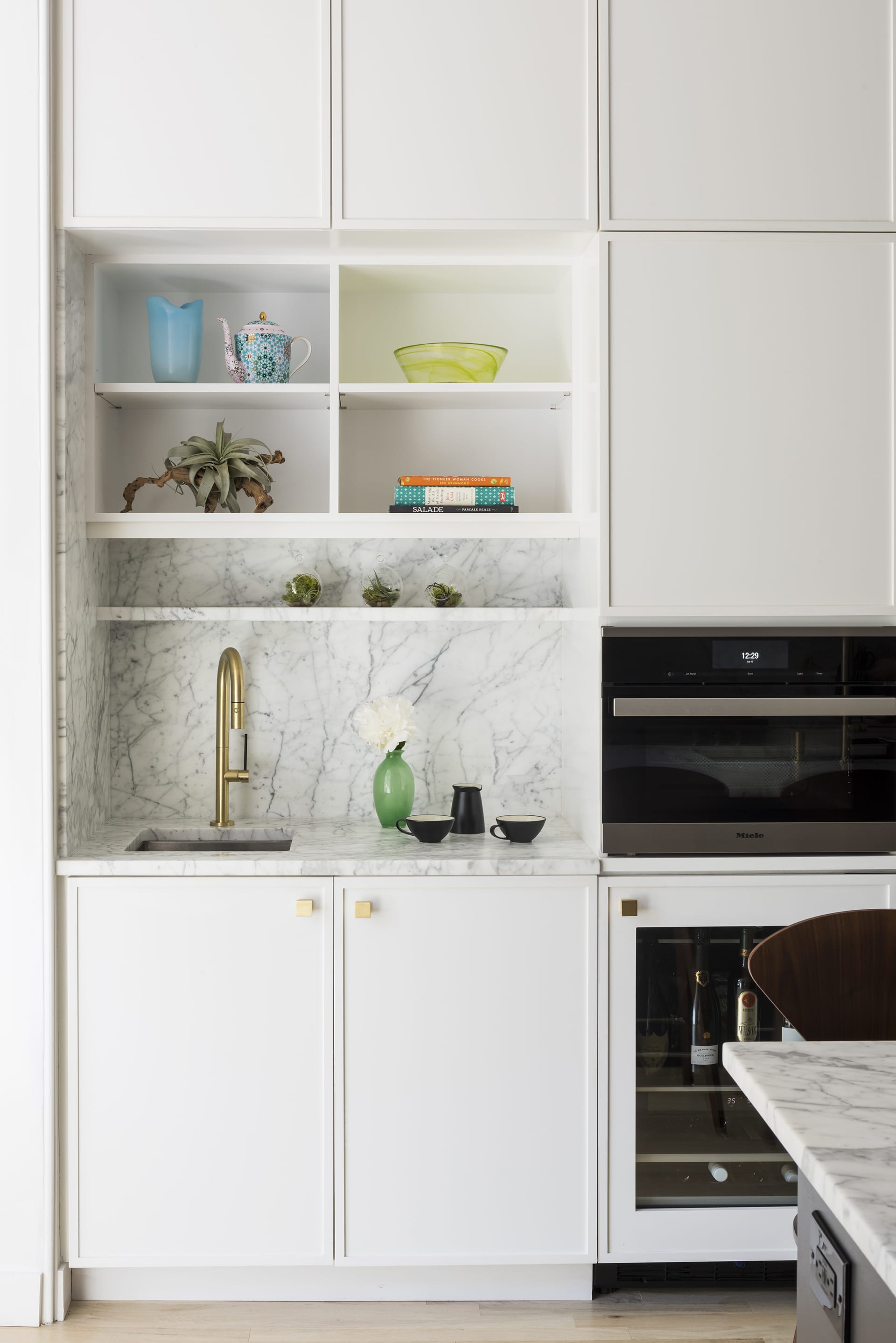 Kitchen in a Prospect Heights home with white millwork, a black island, and white marble countertops