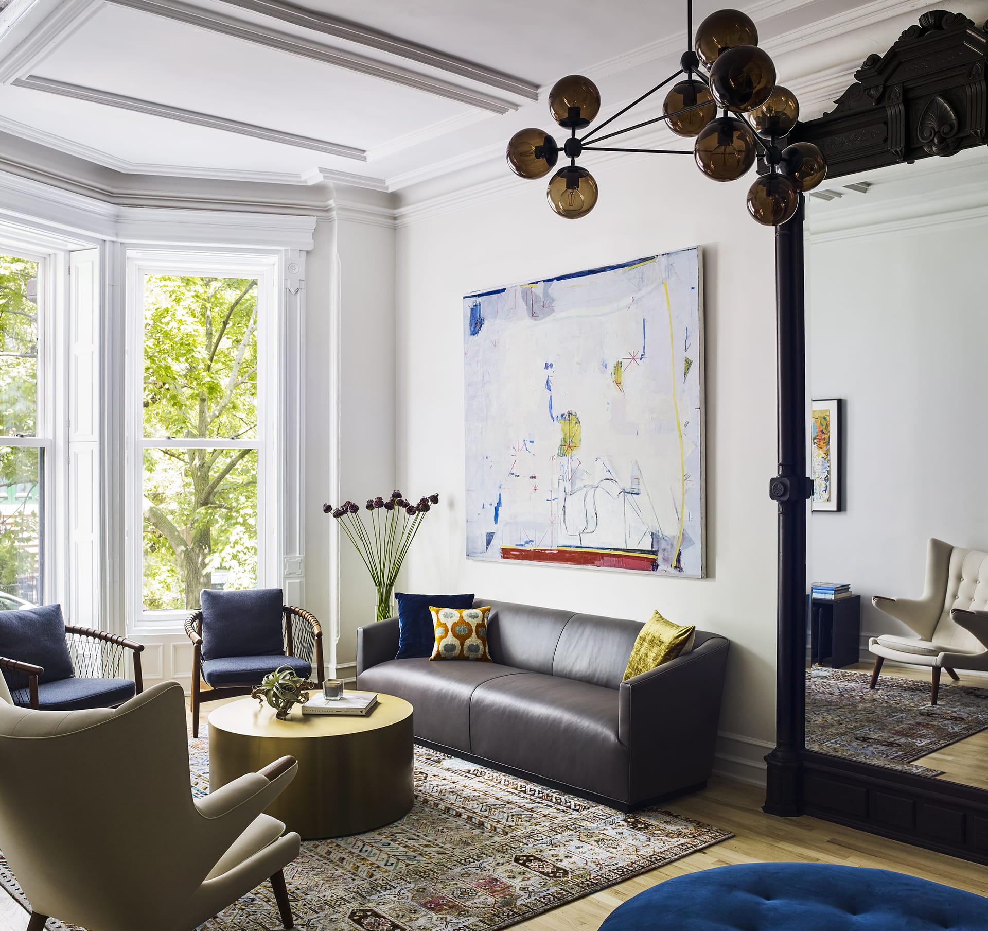 Living room of a Prospect Heights home with a restored, large mirror, large artwork, and mismatched furniture