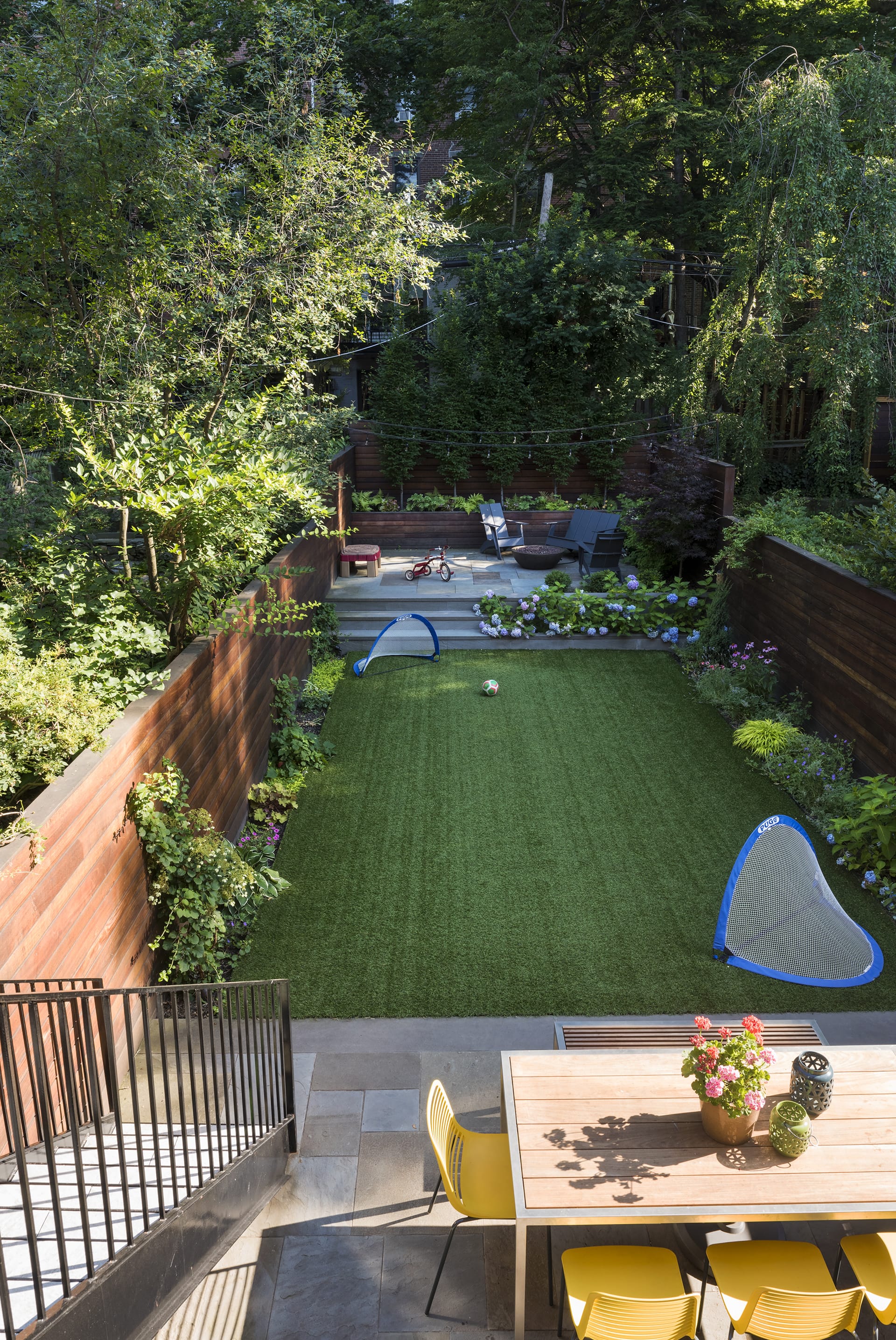 Rear yard after renovation with a wood fence, outdoor table, and large stretch of grass