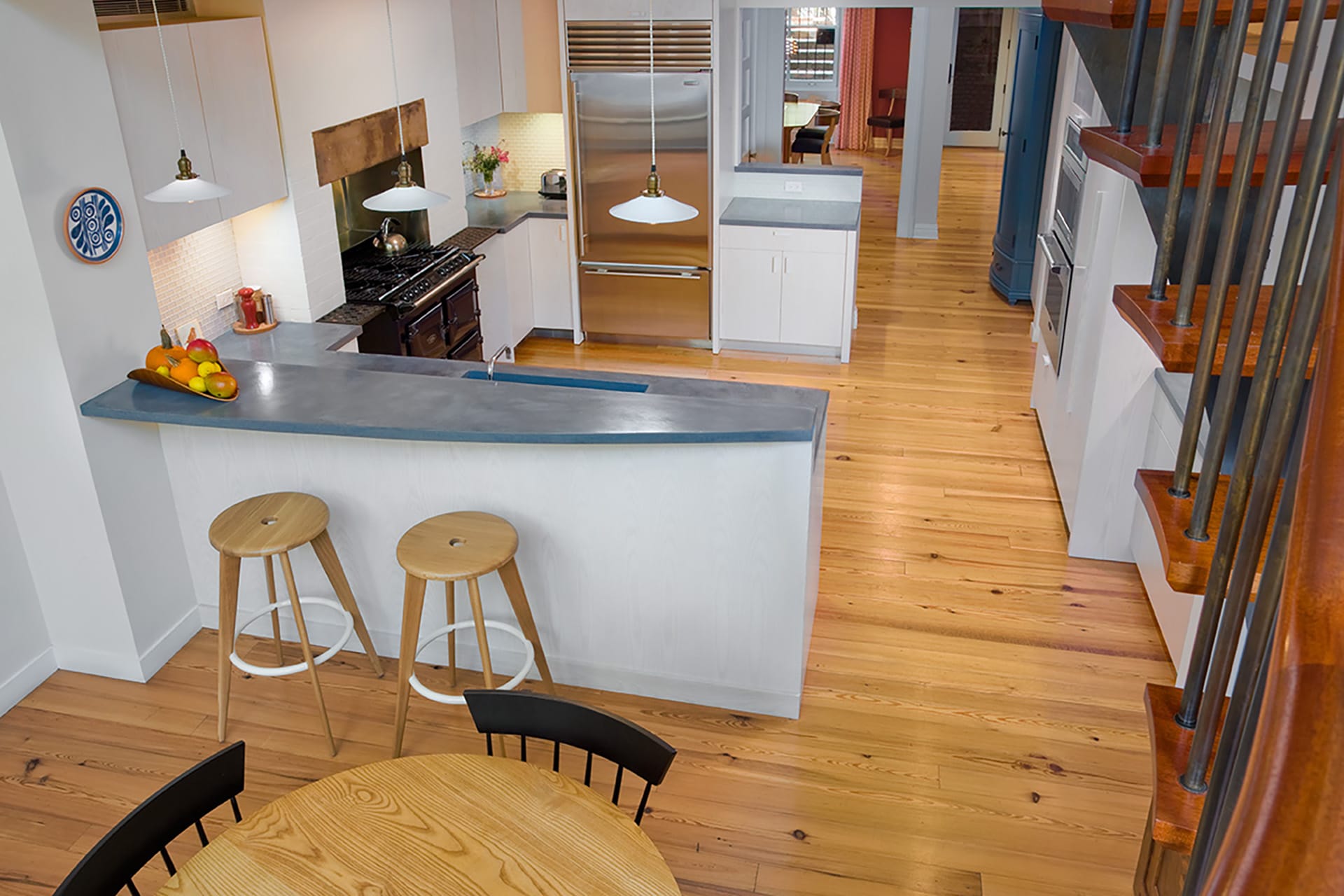 View from staircase of the kitchen in the middle of a Cobble Hill home with blue countertops and white cabinetry.