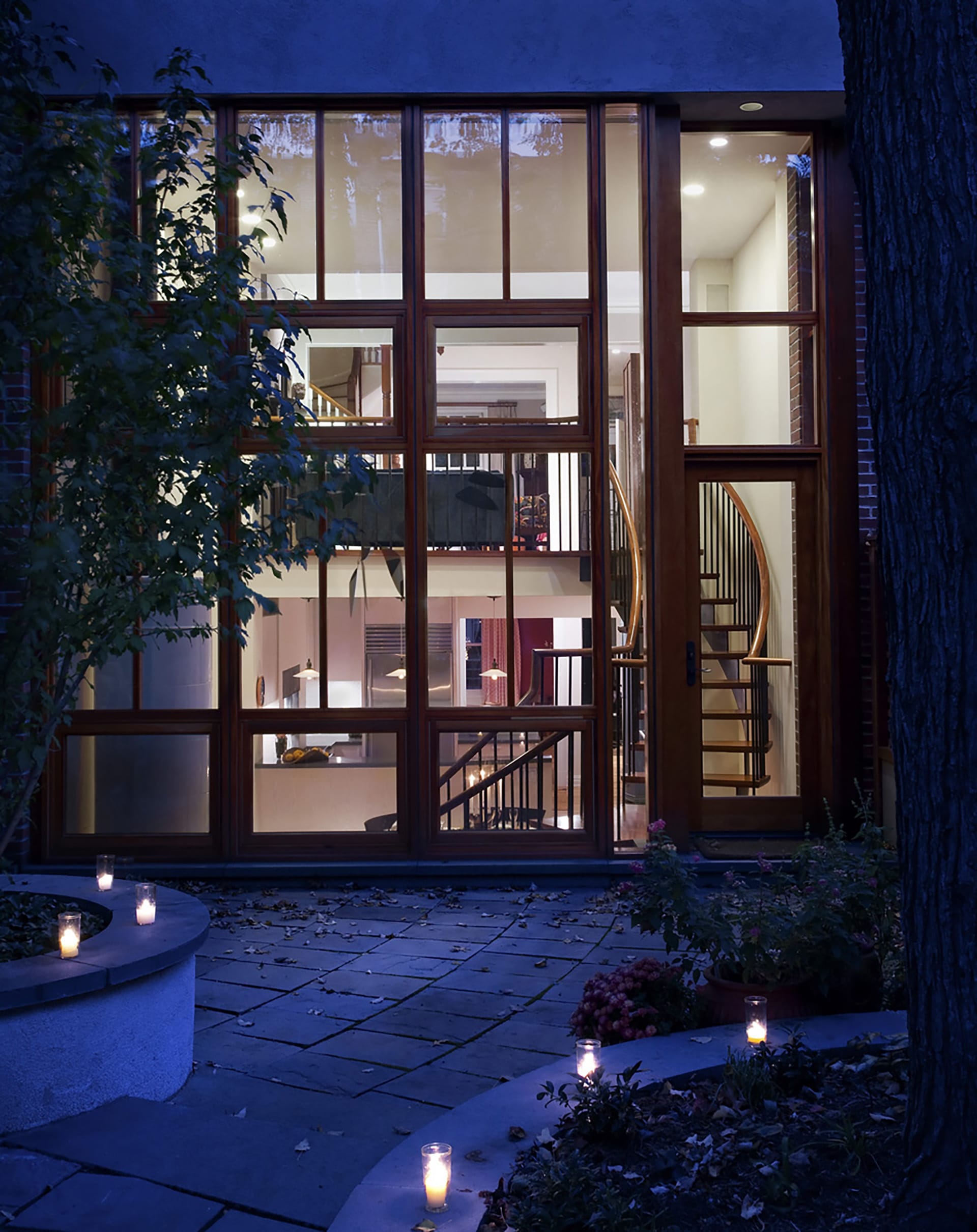 Rear façade of a Cobble Hill townhouse after our renovation with two floors of wall-to-wall glazing at twilight