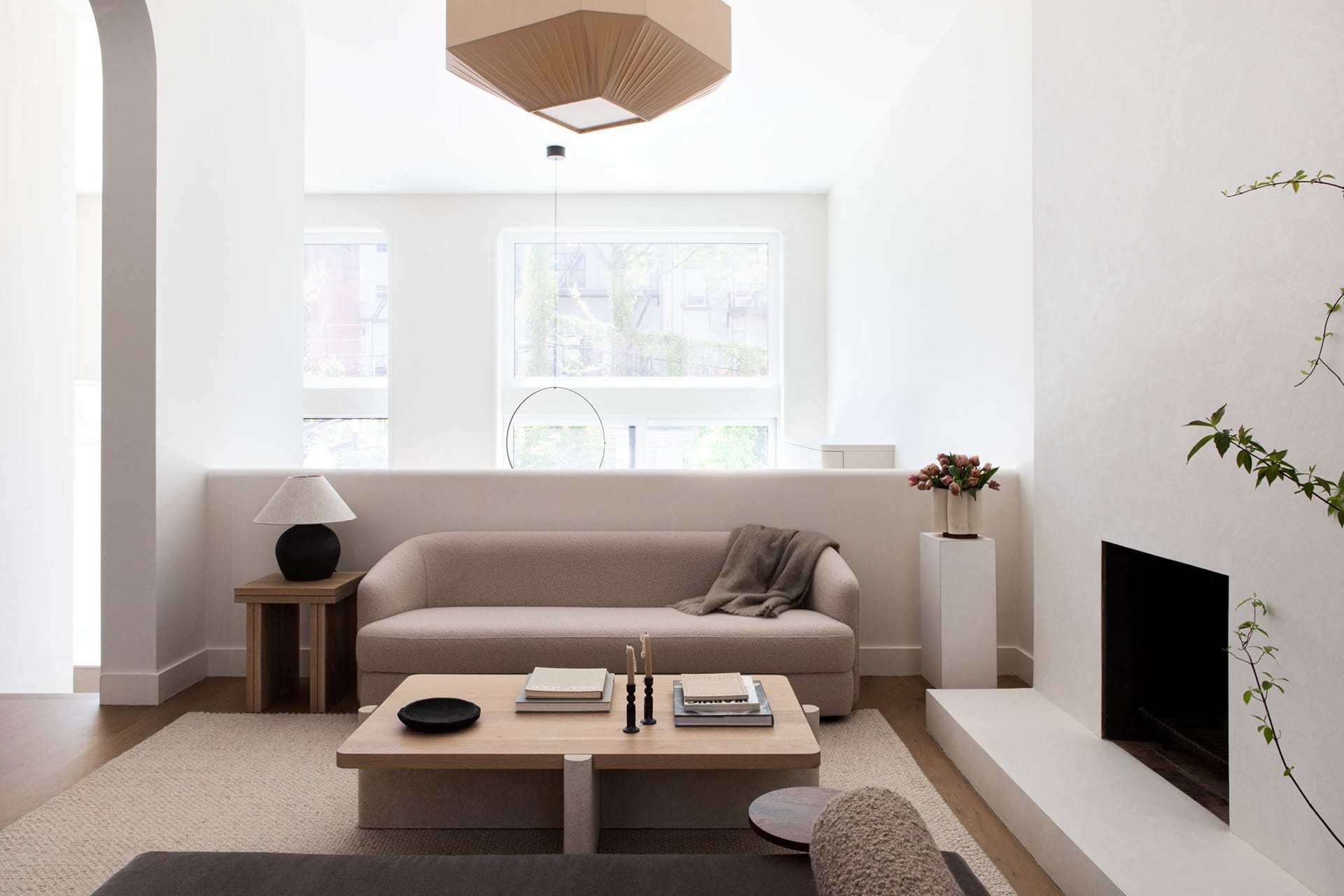 Living room with a white fireplace overlooking a double-height kitchen and large windows.