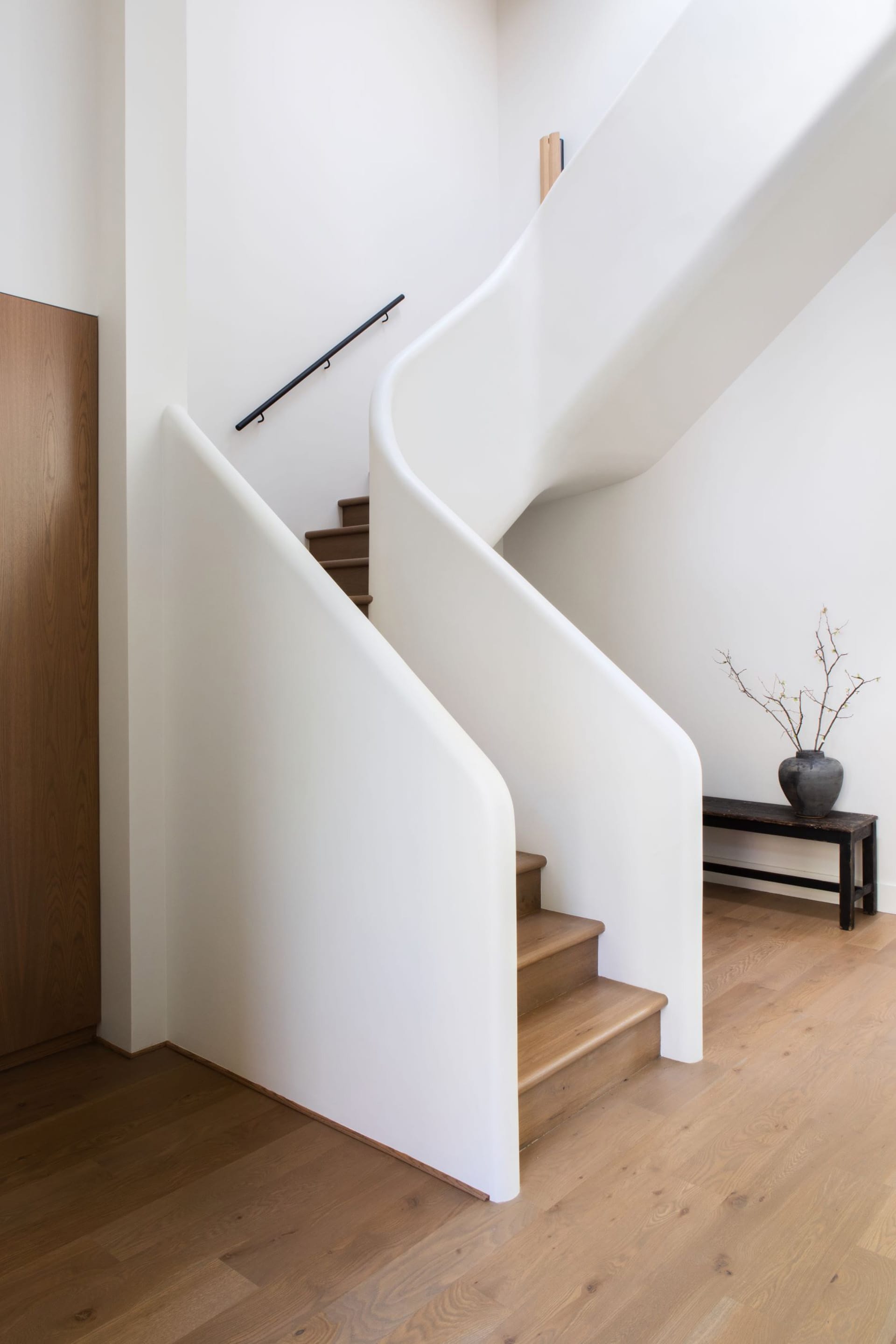 Curved modern staircase landing with white plaster solid railing.
