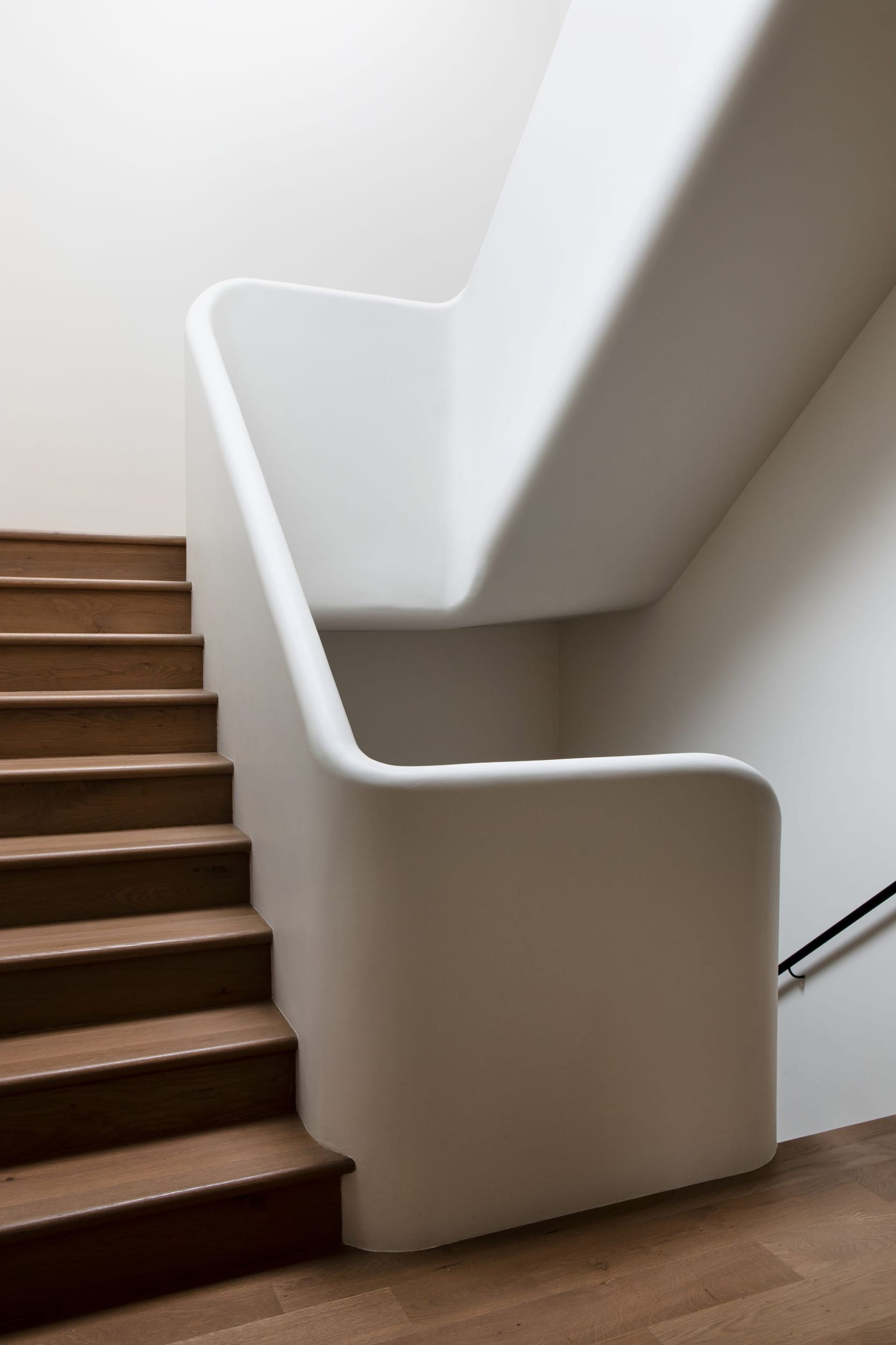 Modern, plaster white curved staircase.