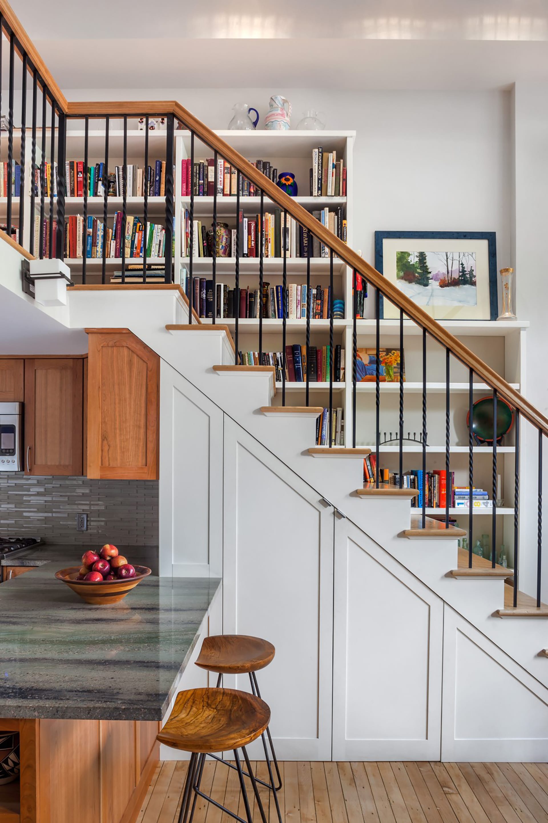Staircase lined with built-in bookshelves and open metal railings.