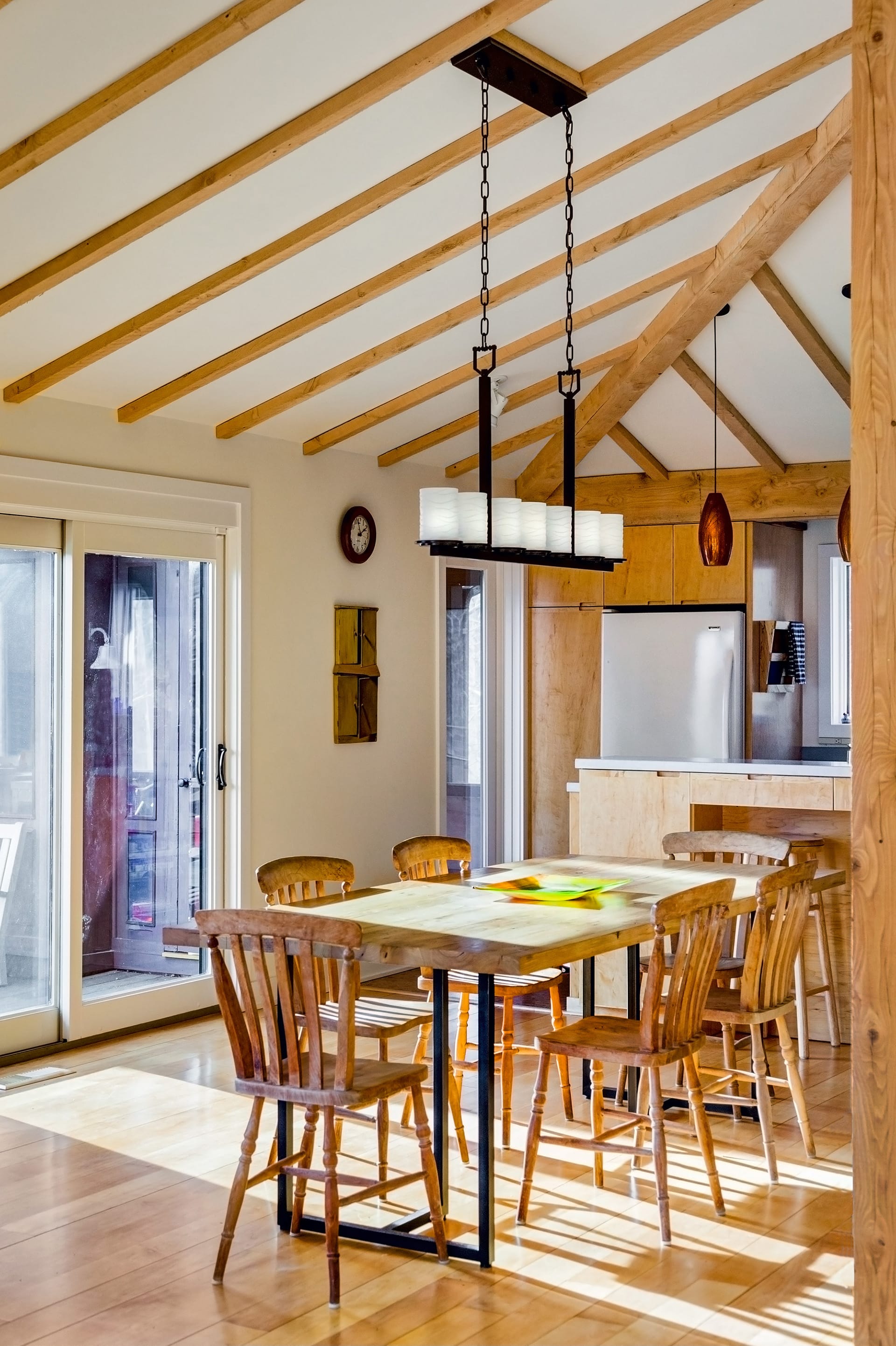 Dining area in front of the kitchen in a Connecticut home. The wooden table matches the floors, cabinetry, and exposed ceiling beams.