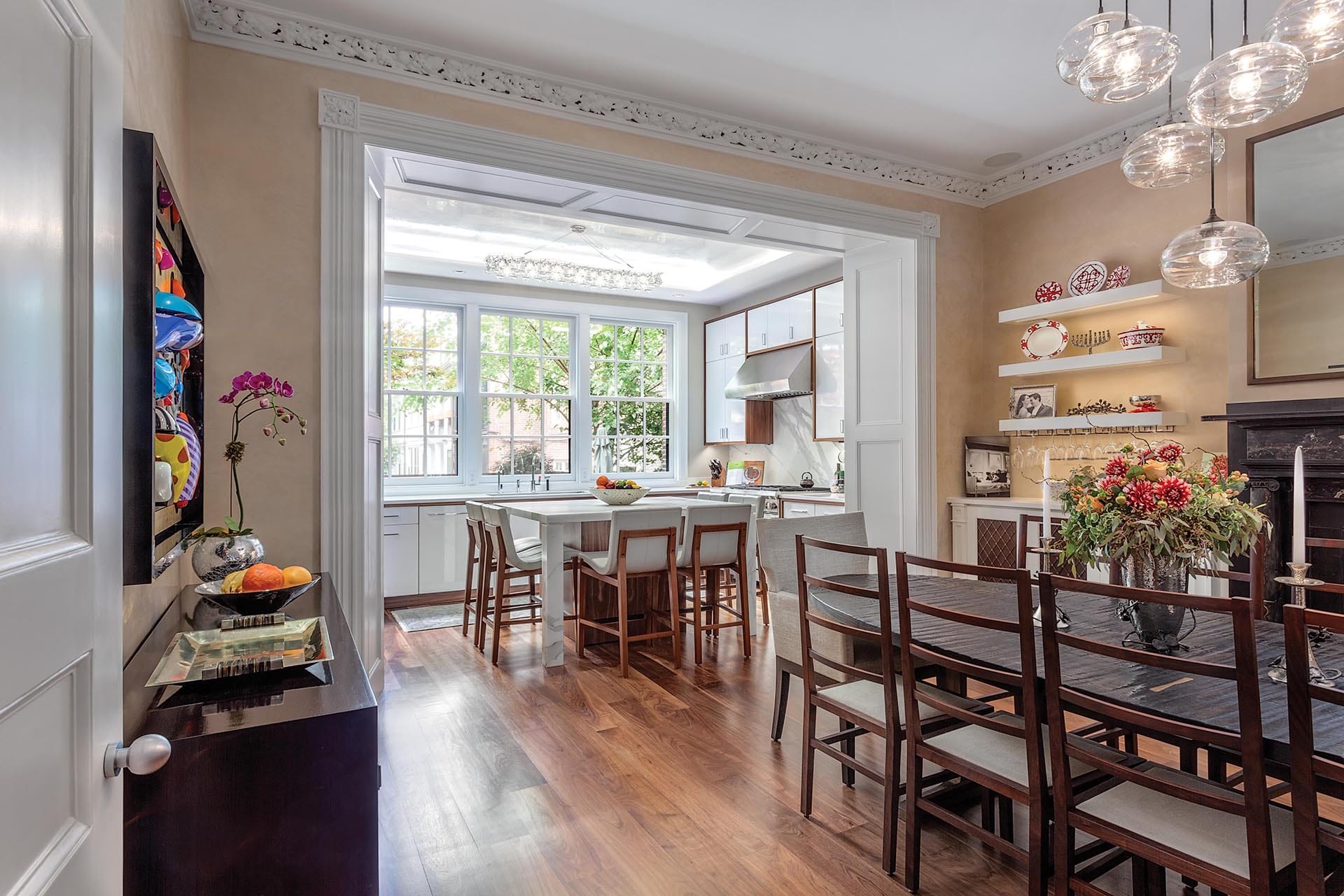 View from dining room to the kitchen with an enlarged opening, preserved crown molding, and modern fuurnishings