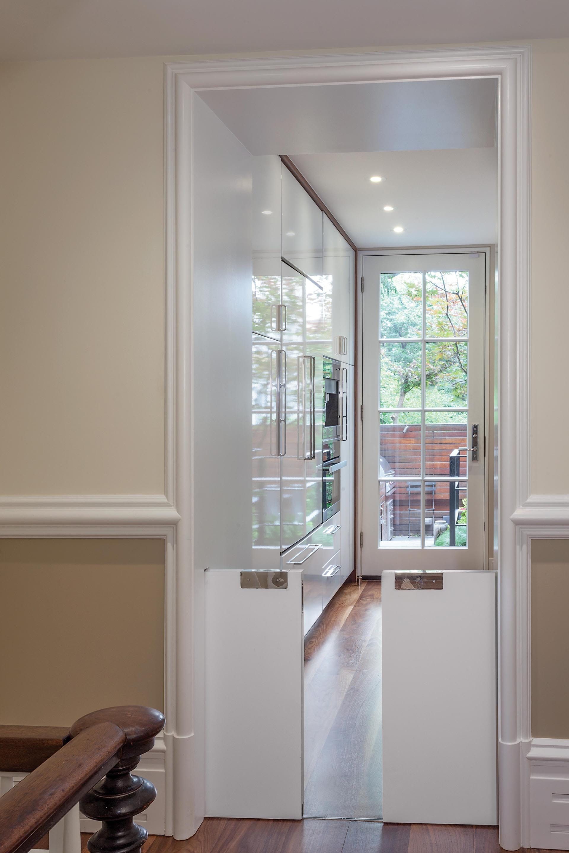 Hallway leading to the kitchen and rear yard with two tiny pocket doors that act as a dog gate