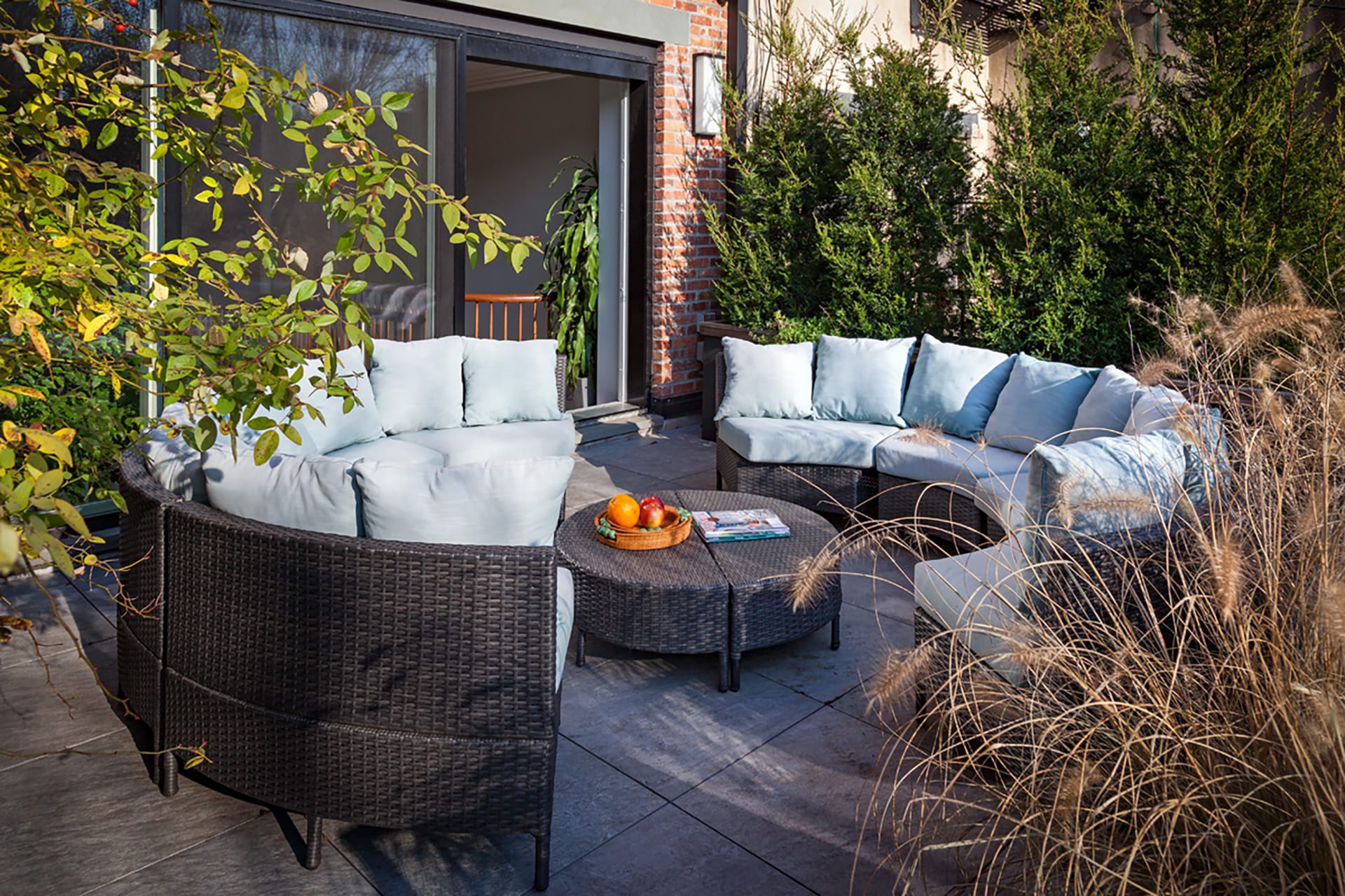 Rear patio with a circular couch and light blue cushions in front of two large sliding glass doors leading inside.