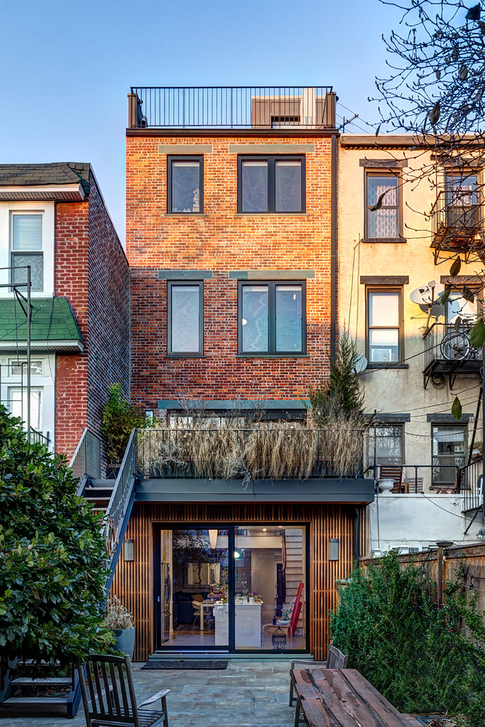 Rear yard of a Carroll Gardens home with an elevated rear deck, and large sliding glass doors leading into the first floor.