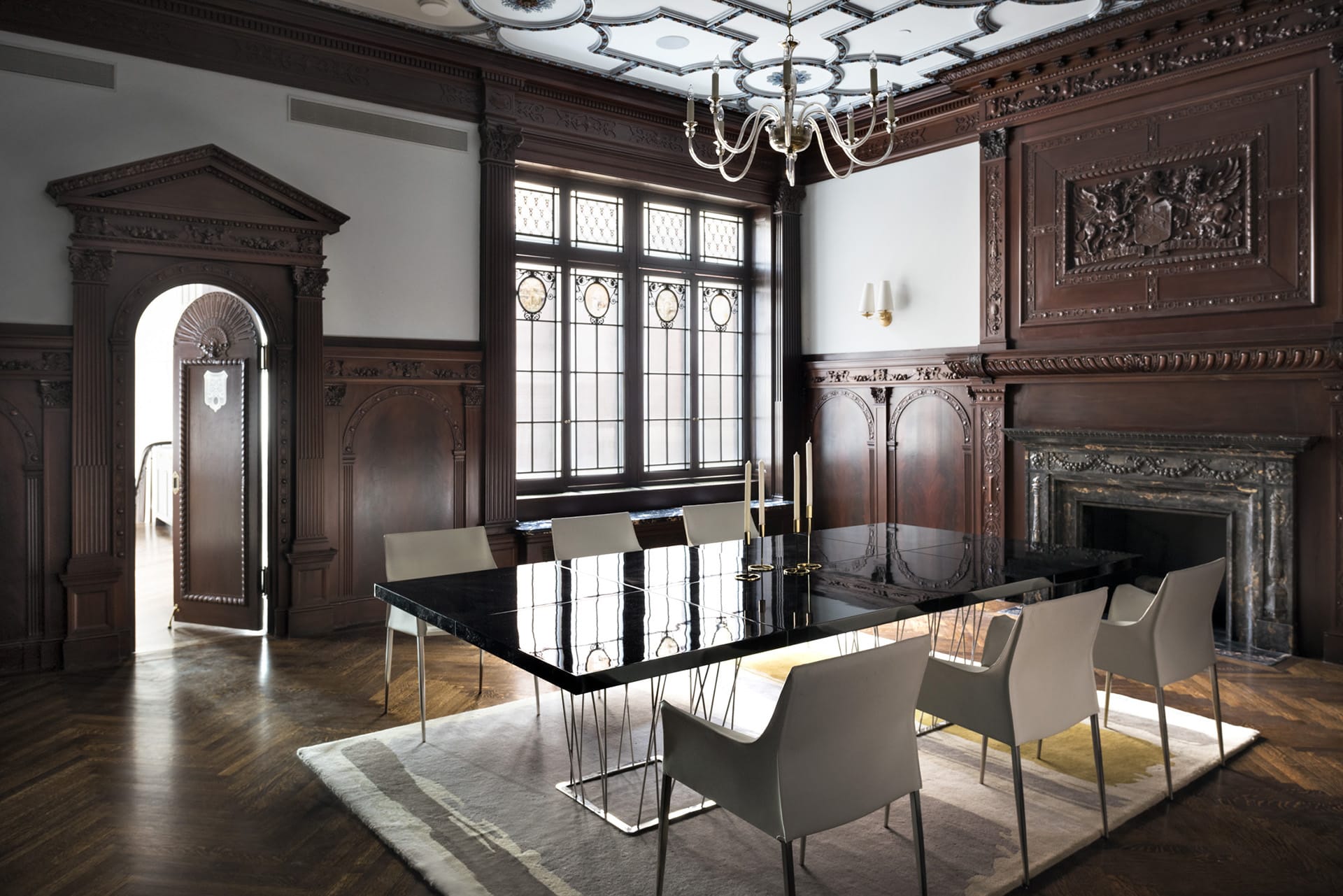 Dining room with contemporary furnishings, a marble fireplace, and carved wood paneling along the walls.