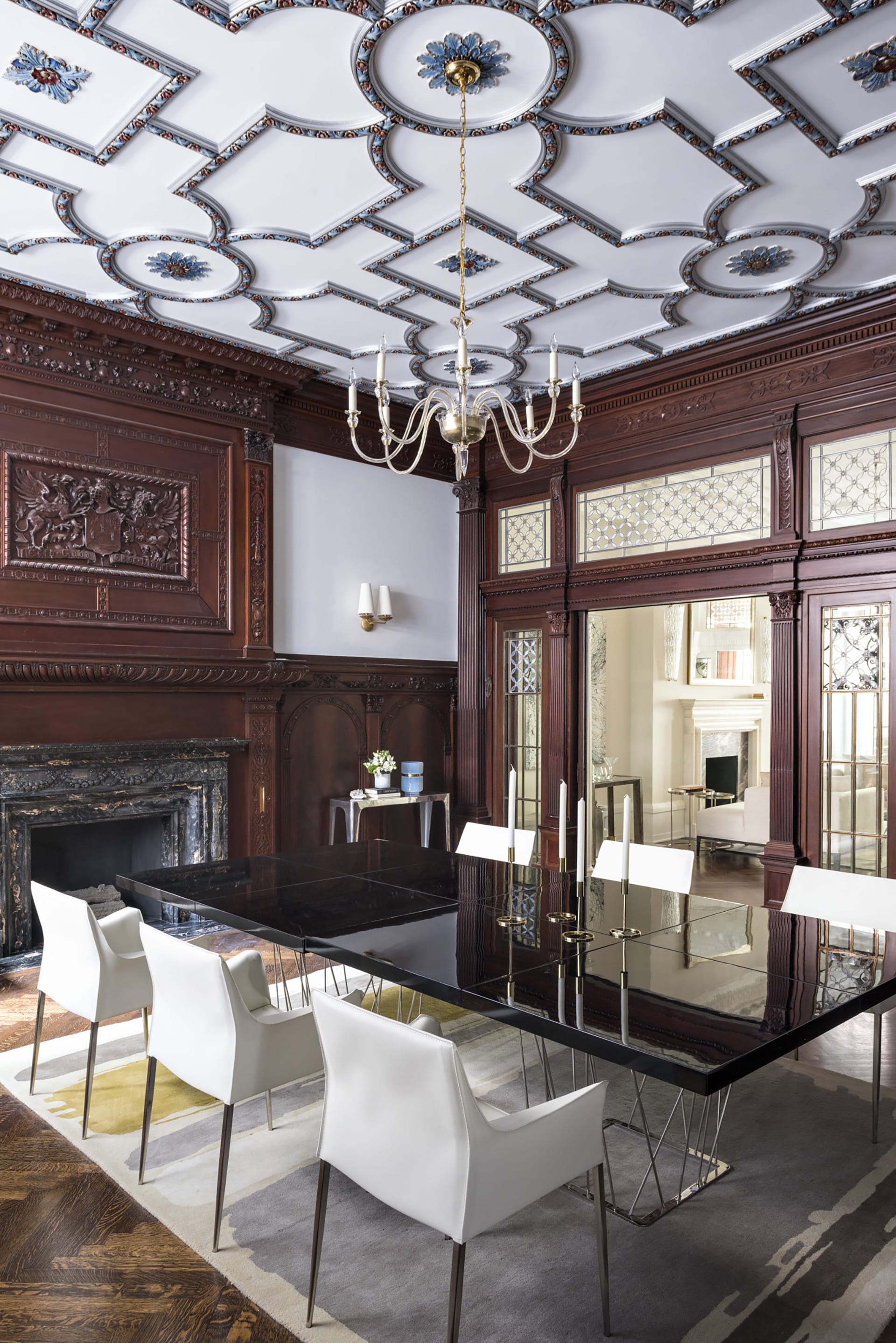Dining room with contemporary furnishings, restored historic windows and ceiling details, and carved wood paneling.