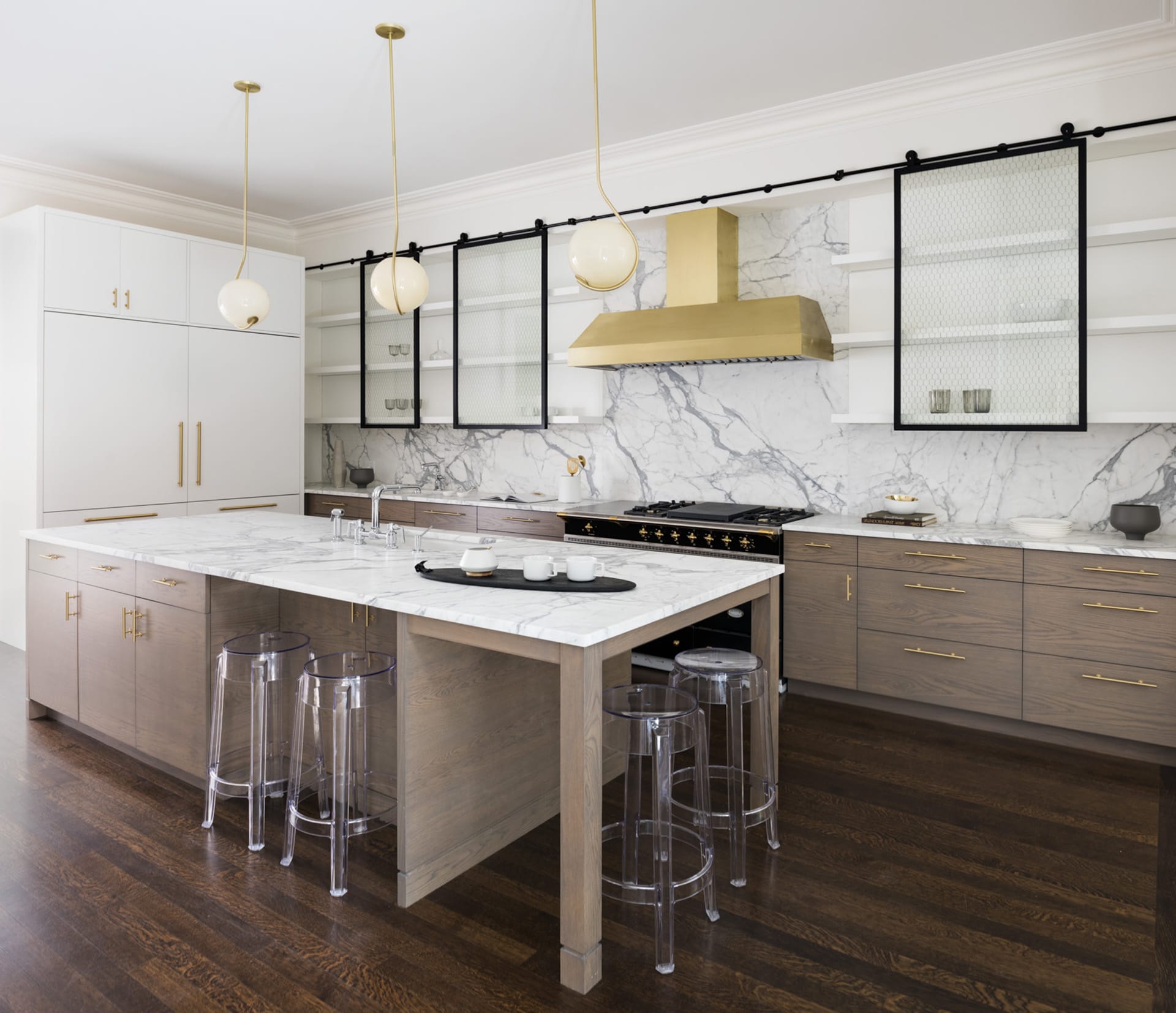 Kitchen with large marble backsplash and countertop, gold fixtures, and a custom farmhouse-style cabinetry system