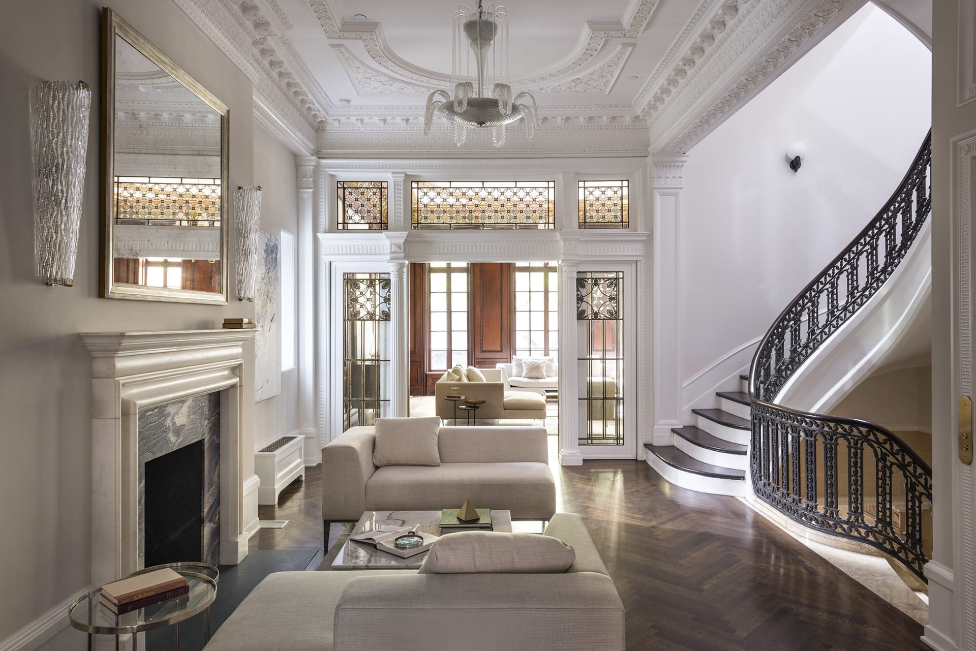 Second-floor landing with a sitting area, intricate detailing on the staircase, ceiling, doors, and moldings, and contemporary furnishings.