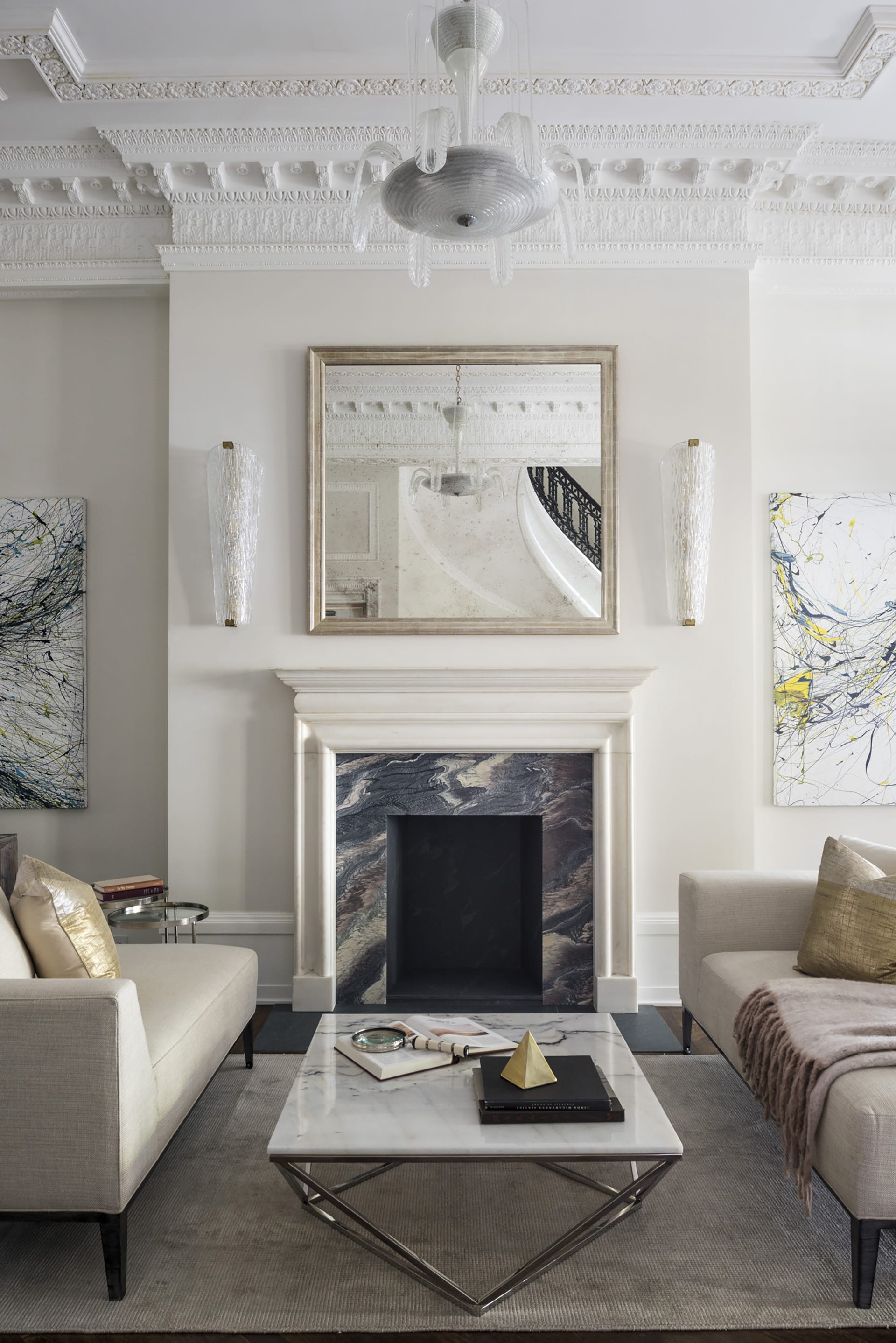 Marble fireplace with contemporary furnishings, a chandelier, and intricate crown molding details.