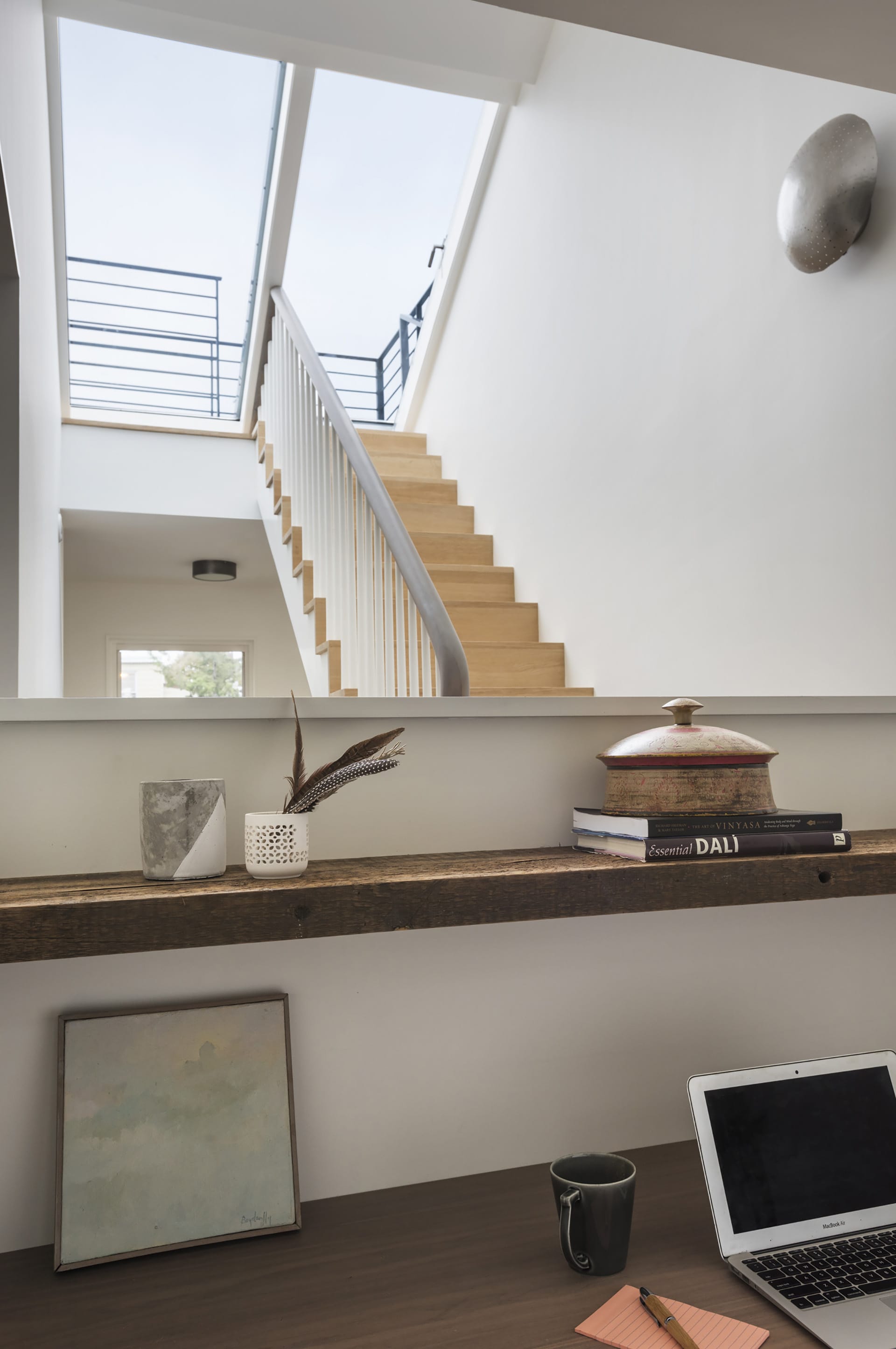 Stair hallway leading to sliding skylight roof hatch door, wood staircase, and a desk in the foreground