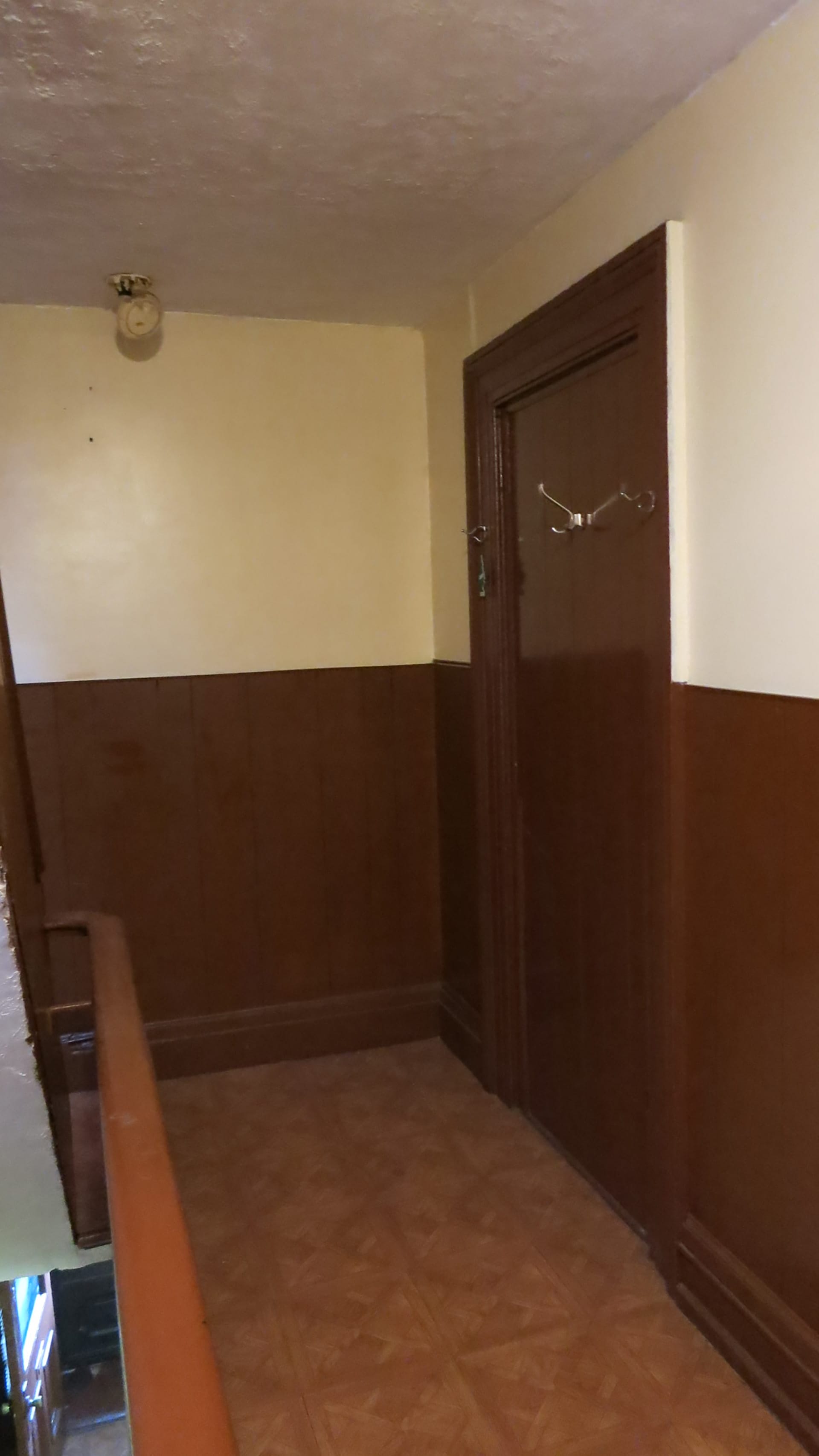 Stair hallway with dark wood paneling and door, before our renovation